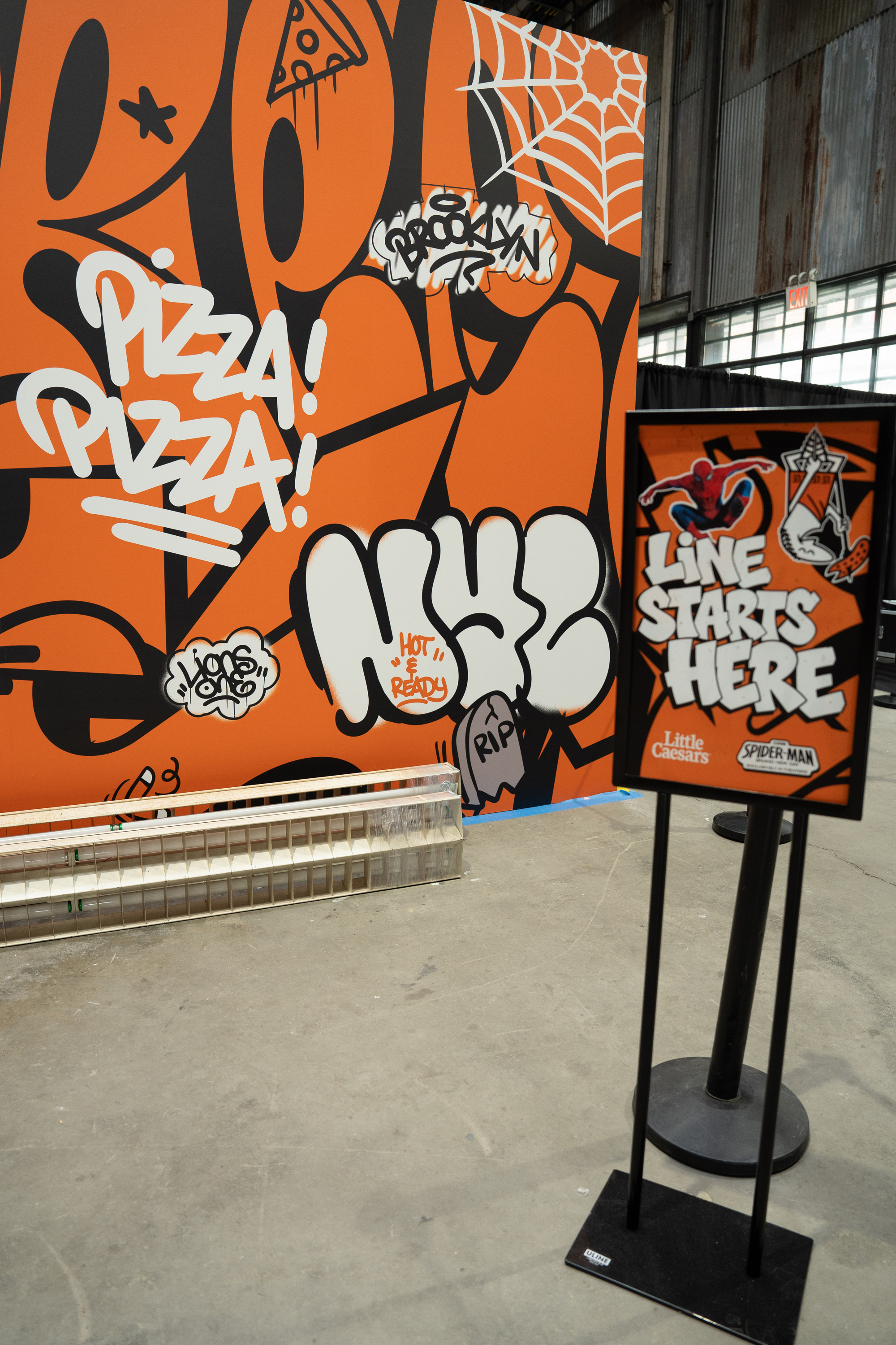 Pizza Pizza and NYC graffiti wall with a Line Starts Here queue sign