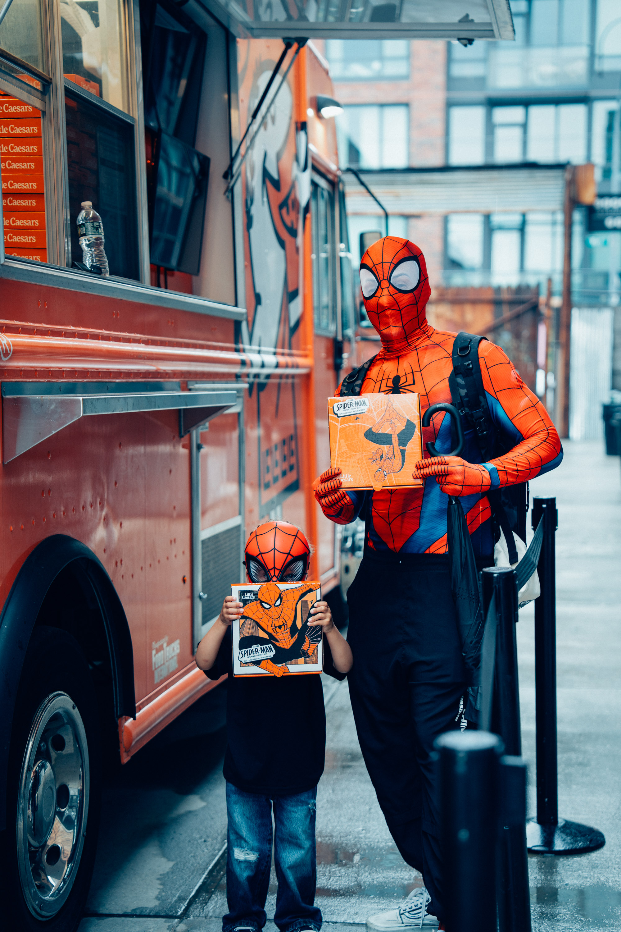 Spider-Man and a young fan with pizza boxes at the truck